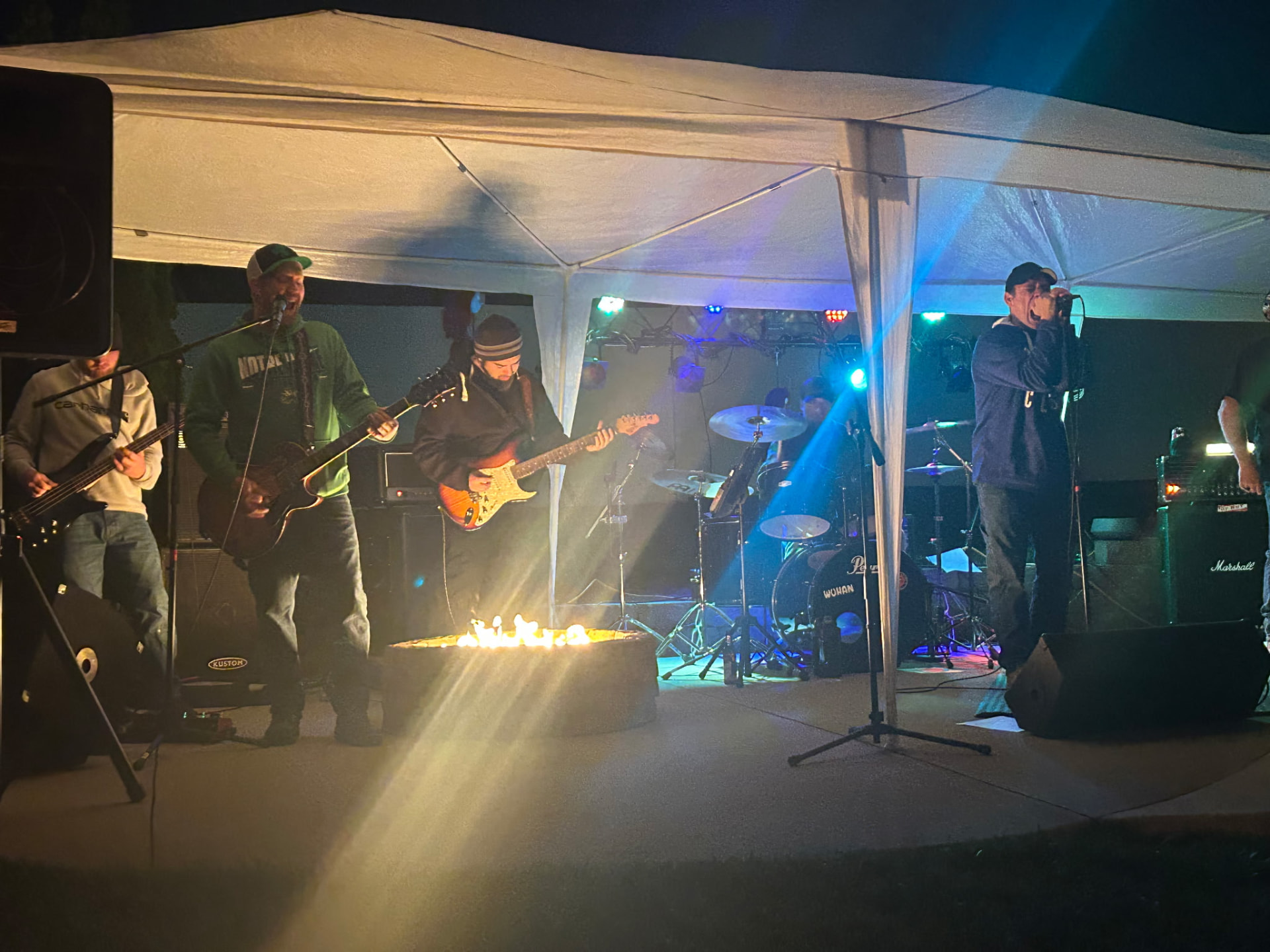 Piece of Me playing under a marquee beside a fire pit at night