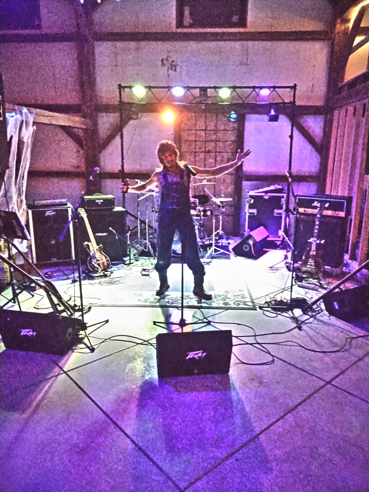 Singer arms wide on the barn stage under purple light