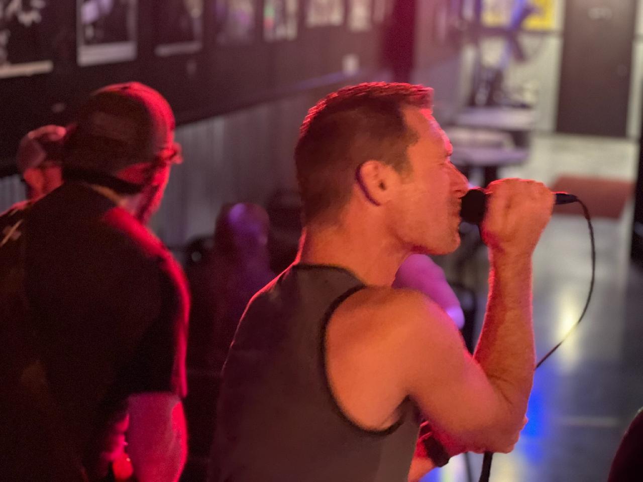Singer belting into the mic under red light